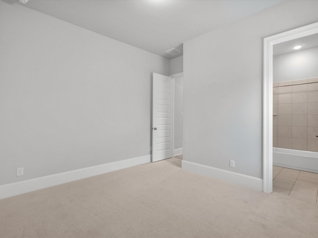 unfurnished bedroom featuring ensuite bath, carpet flooring, visible vents, and baseboards