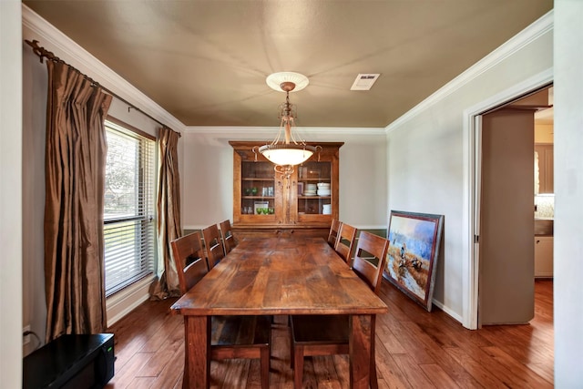 dining room with visible vents, crown molding, baseboards, and hardwood / wood-style flooring