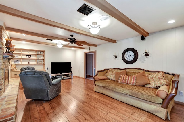 living room featuring a ceiling fan, beamed ceiling, wood finished floors, and visible vents