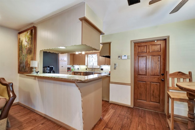 kitchen featuring backsplash, a peninsula, light wood-type flooring, and ceiling fan