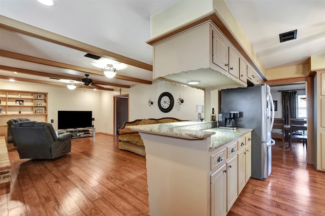 kitchen featuring light wood-type flooring, visible vents, light stone countertops, and beamed ceiling