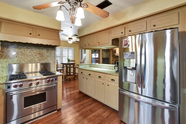 kitchen featuring light countertops, a peninsula, cream cabinets, wood finished floors, and stainless steel appliances