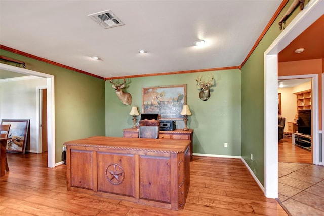 office area with light wood finished floors, visible vents, baseboards, and ornamental molding