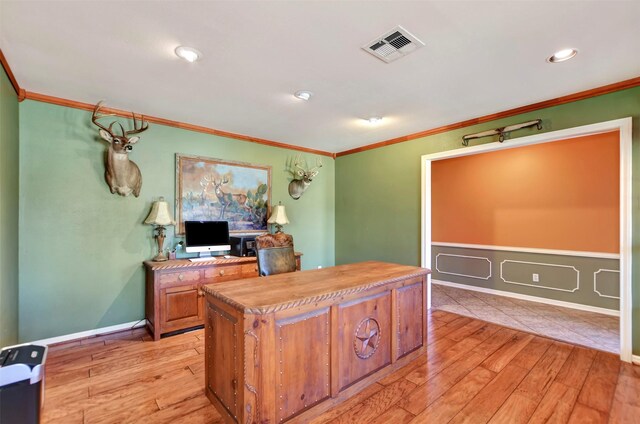 office space featuring baseboards, visible vents, light wood finished floors, and ornamental molding