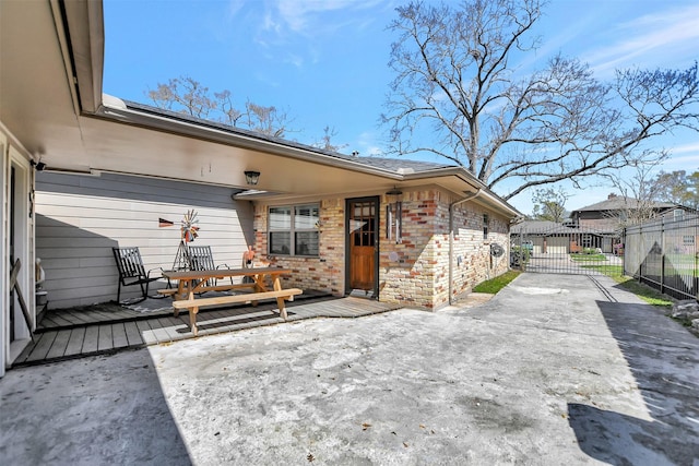 back of property with brick siding, a wooden deck, and fence