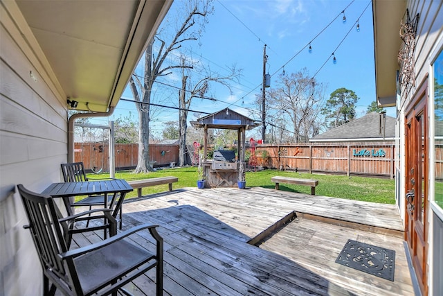 wooden deck with grilling area, a lawn, and a fenced backyard