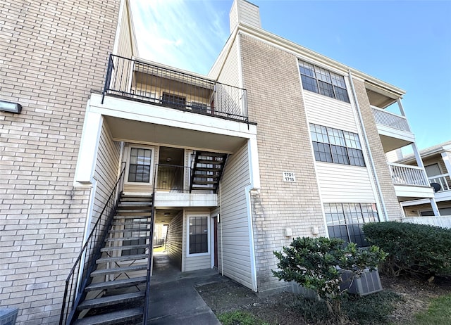 view of building exterior with stairs and central AC