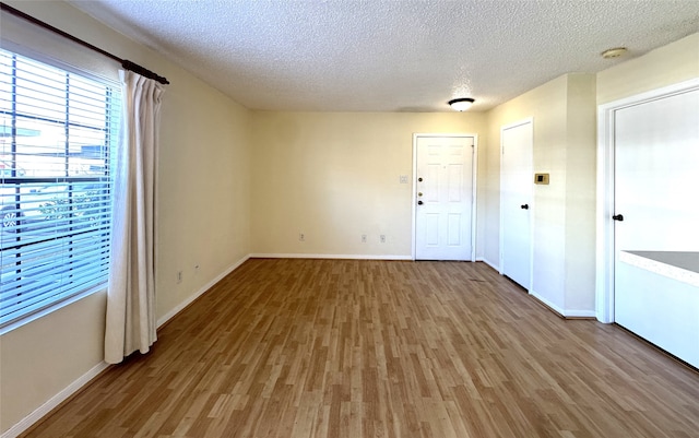 spare room featuring baseboards, a textured ceiling, and light wood-style flooring