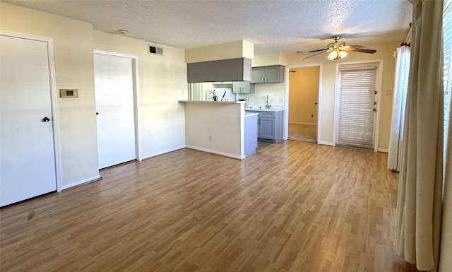 kitchen featuring visible vents, gray cabinetry, a textured ceiling, wood finished floors, and light countertops