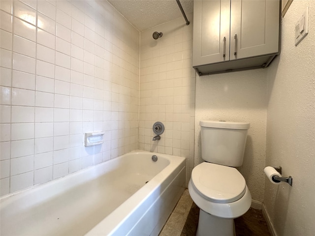 bathroom with baseboards, toilet, shower / bathtub combination, a textured wall, and a textured ceiling