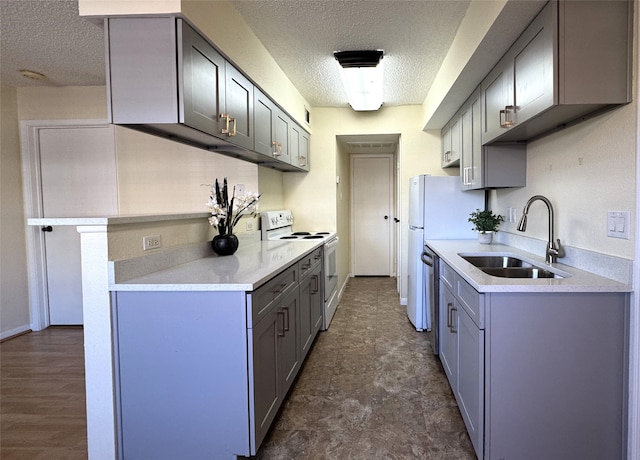 kitchen with gray cabinetry, a sink, a textured ceiling, white range with electric stovetop, and light countertops