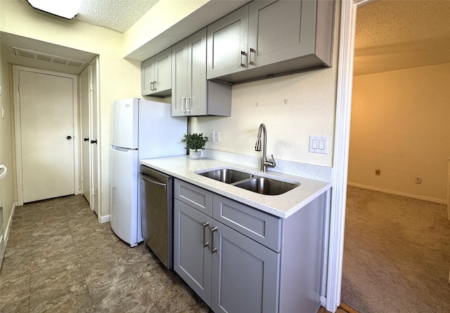 kitchen featuring gray cabinetry, a sink, stainless steel dishwasher, a textured ceiling, and light countertops