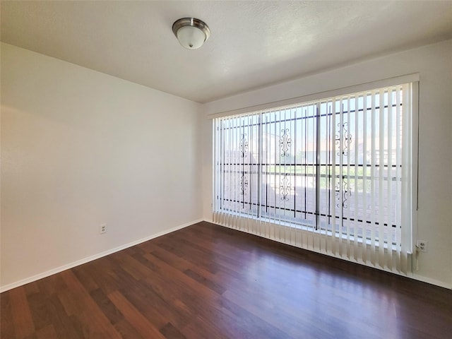 unfurnished room featuring dark wood finished floors and baseboards