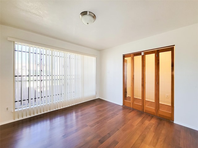 unfurnished bedroom with a closet, baseboards, and wood finished floors