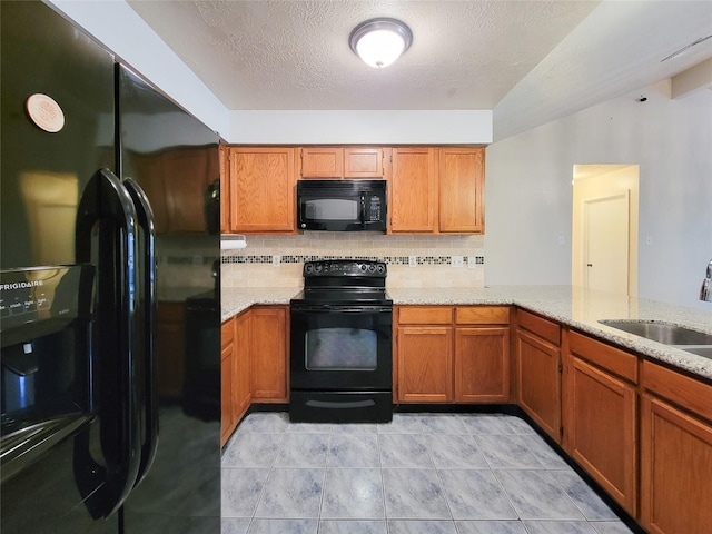 kitchen with a sink, black appliances, and brown cabinetry