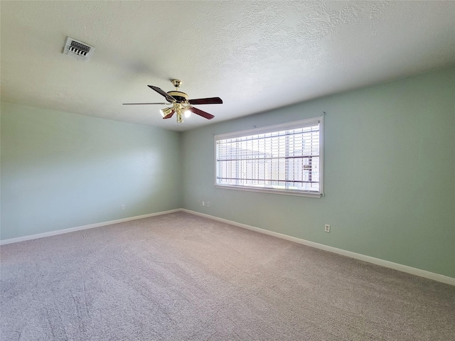 carpeted spare room with a ceiling fan, baseboards, visible vents, and a textured ceiling