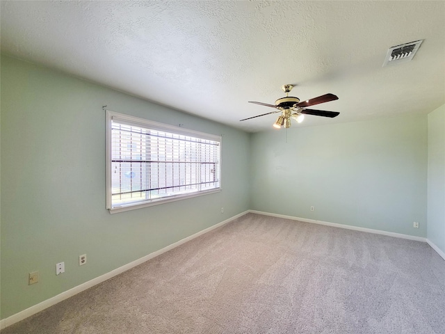 empty room with carpet, a ceiling fan, baseboards, visible vents, and a textured ceiling