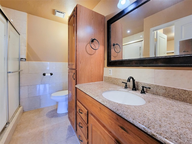 bathroom with tile patterned flooring, visible vents, a shower stall, toilet, and tile walls