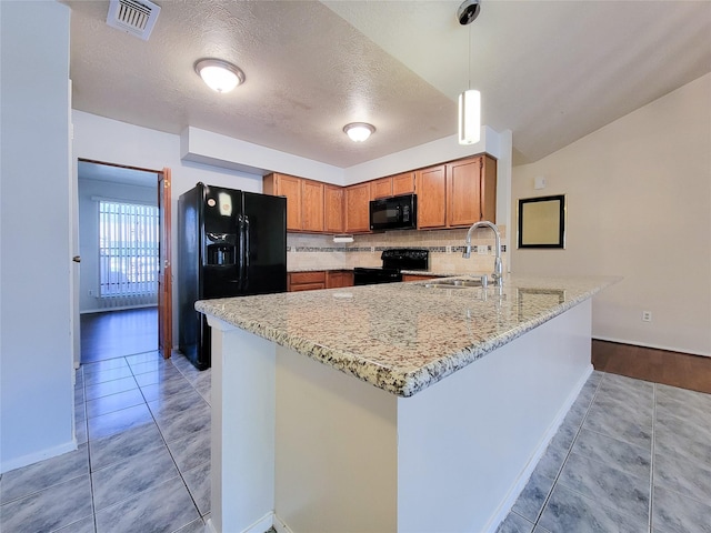 kitchen featuring visible vents, black appliances, a sink, tasteful backsplash, and a peninsula