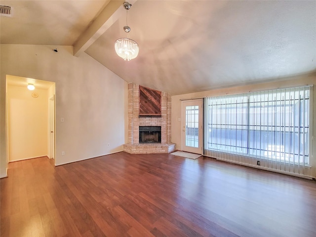 unfurnished living room featuring visible vents, a large fireplace, a chandelier, lofted ceiling with beams, and wood finished floors