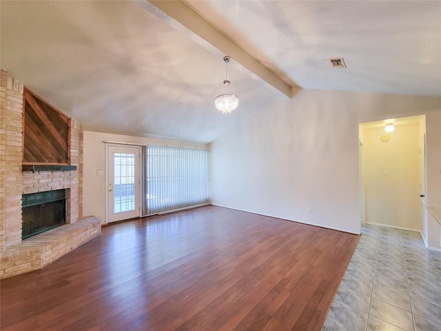 unfurnished living room with visible vents, a brick fireplace, wood finished floors, and vaulted ceiling with beams