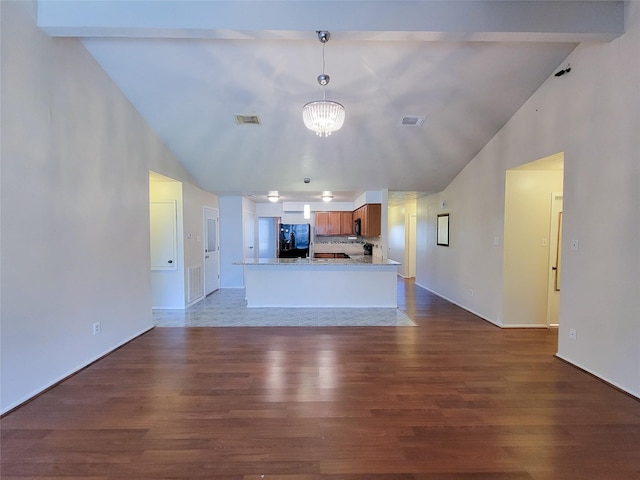 kitchen featuring brown cabinets, visible vents, dark wood-style flooring, and black fridge