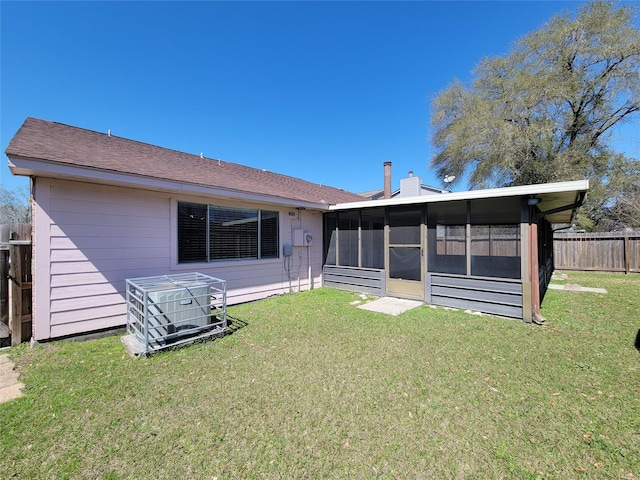 back of property with fence, a lawn, a sunroom, and a chimney