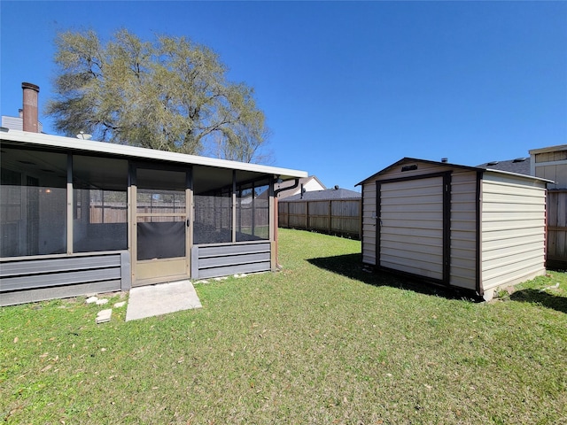 view of yard with an outbuilding, a shed, fence, and a sunroom