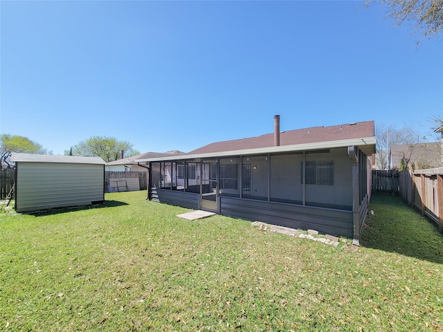 rear view of house featuring a fenced backyard, a yard, a storage shed, an outdoor structure, and a sunroom