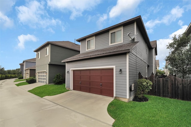 traditional-style home featuring an attached garage, roof with shingles, a front lawn, and fence