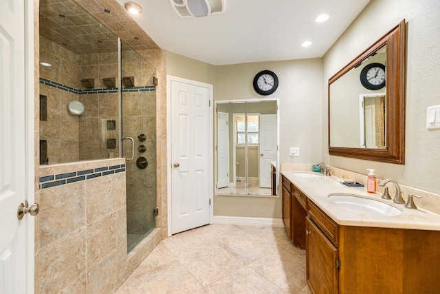 full bathroom featuring visible vents, baseboards, double vanity, a stall shower, and a sink