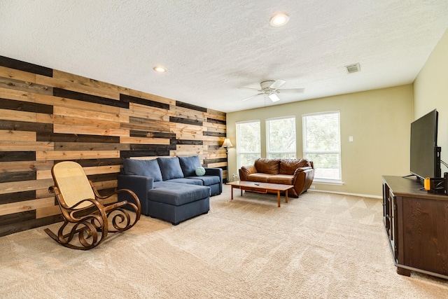 living room featuring visible vents, light carpet, a textured ceiling, recessed lighting, and wood walls