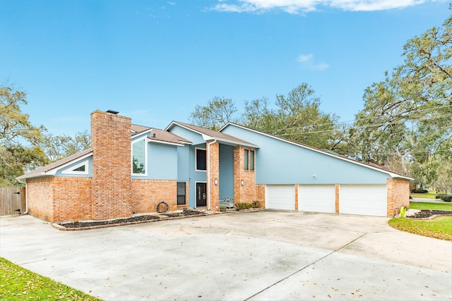 mid-century modern home with brick siding, driveway, a chimney, and a garage