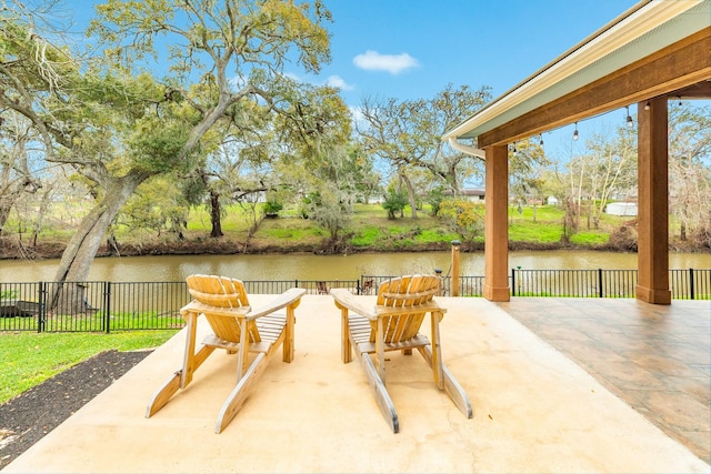 view of patio featuring fence and a water view