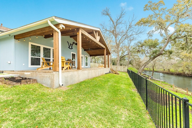 view of yard with a patio, a fenced backyard, a ceiling fan, and a water view