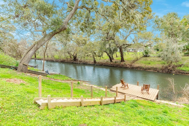 view of dock with a lawn and a water view