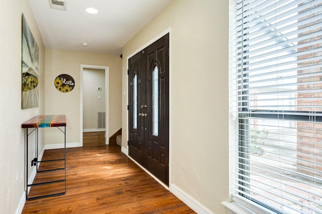 foyer entrance with visible vents, baseboards, and wood finished floors