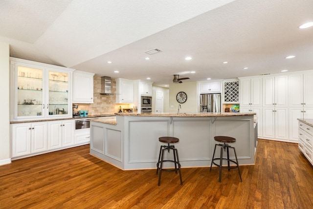 kitchen featuring visible vents, appliances with stainless steel finishes, white cabinets, wall chimney range hood, and dark wood-style flooring