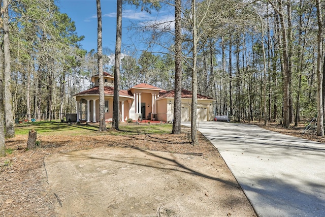 mediterranean / spanish-style house with stucco siding, an attached garage, a tile roof, and driveway