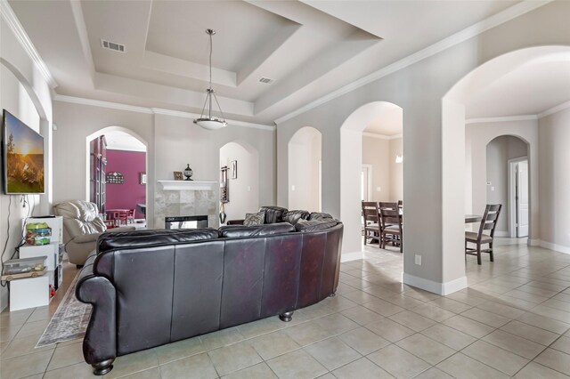 living room featuring a tray ceiling, light tile patterned flooring, a fireplace, and visible vents