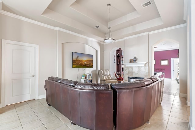 living area featuring light tile patterned floors, visible vents, arched walkways, and a tray ceiling