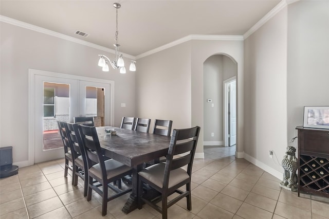 dining room featuring arched walkways, visible vents, crown molding, and light tile patterned flooring