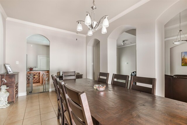 dining area with light tile patterned floors, arched walkways, a notable chandelier, and ornamental molding