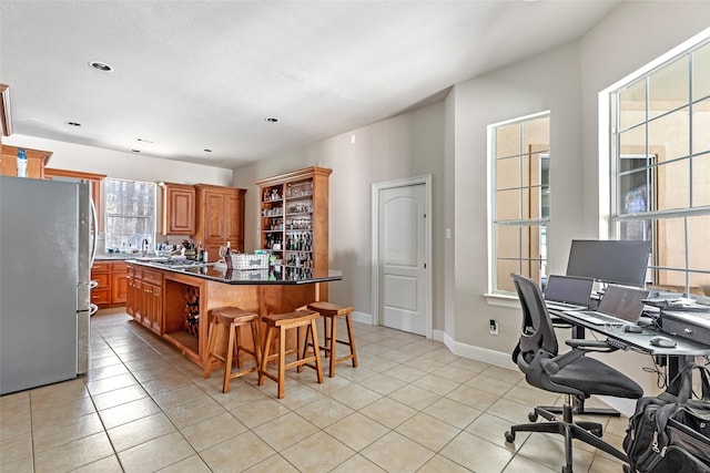21971 Blazing Trl, New Caney, TX 77357 - kitchen featuring a kitchen island, open shelves, freestanding refrigerator, a kitchen bar, and light tile patterned floors