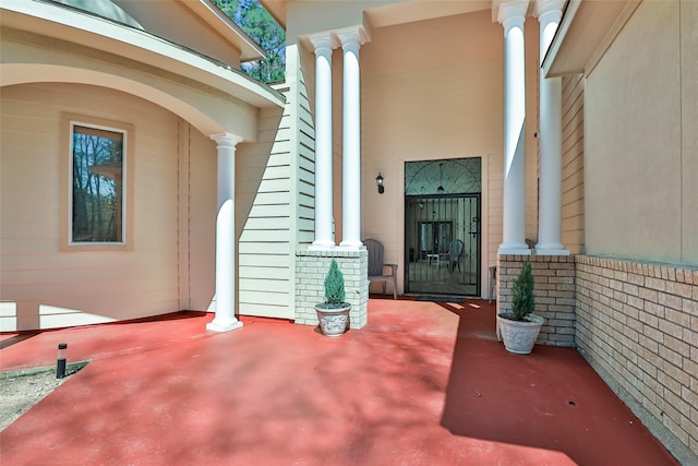 doorway to property featuring covered porch and brick siding