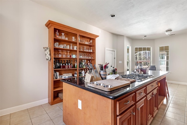 kitchen with stainless steel gas cooktop, open shelves, baseboards, and light tile patterned flooring