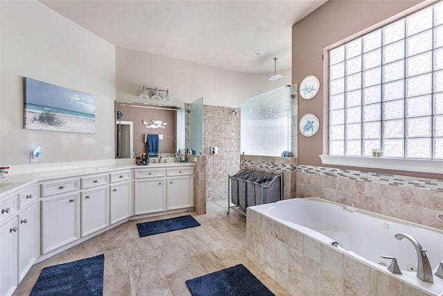 bathroom featuring walk in shower, a tub with jets, and vanity