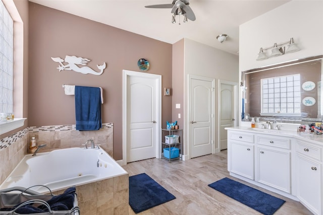 bathroom with a tub with jets, vanity, ceiling fan, and wood finished floors