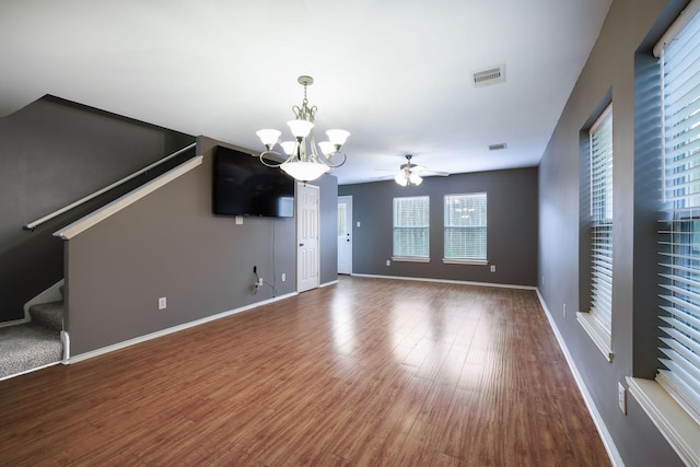 unfurnished living room with visible vents, baseboards, stairway, ceiling fan with notable chandelier, and wood finished floors