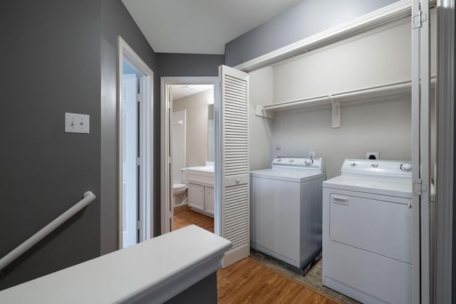 clothes washing area featuring separate washer and dryer, light wood-style flooring, and laundry area